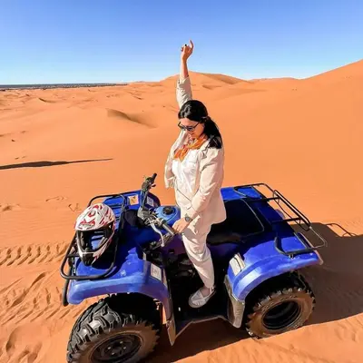 a woman standing on a wheeler in the desert at Bivouac la fibule des Dunes in Merzouga