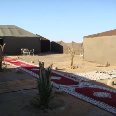 a patio with a table and a rug on the ground at Bivouac la fibule des Dunes in Merzouga