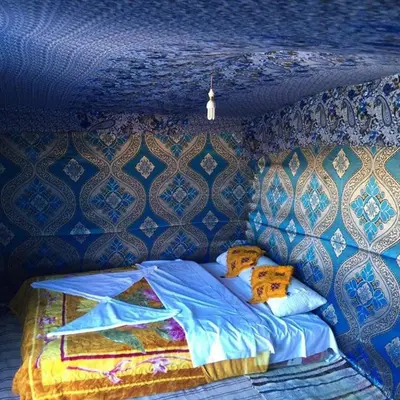 a bed in a room with a blue ceiling at Bivouac la fibule des Dunes in Merzouga