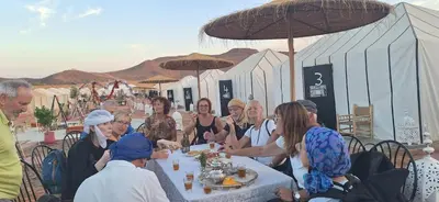 a group of people sitting at a table eating at LUXURY Camp in Merzouga