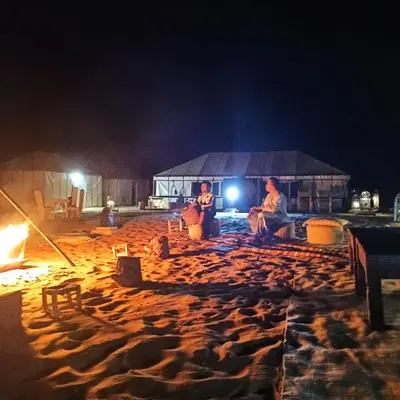 a group of people sitting on the beach at night at LUXURY Camp in Merzouga