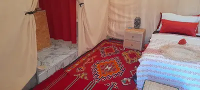 a bedroom with a bed and a red rug at LUXURY Camp in Merzouga