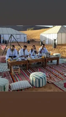 a group of people sitting at a picnic table on the beach at LUXURY Camp in Merzouga