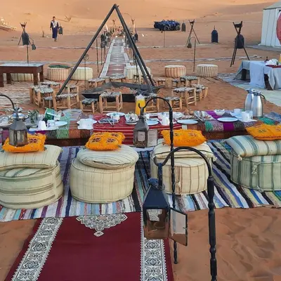 a table in the middle of a desert with a table with food at LUXURY Camp in Merzouga