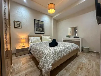 a bedroom with a bed with a chair on it at Appartement Luxueux, 2 chambres, à 300m de la Gare de train in Fès