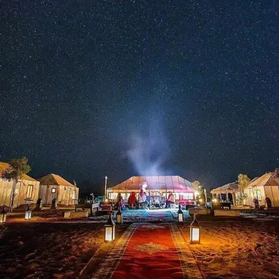 a lit up building under a starry sky at night at Luxury Desert Camp Merzouga in Merzouga