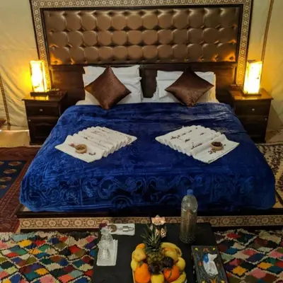 a bed with two towels and a table with fruit on it at Luxury Desert Camp Merzouga in Merzouga