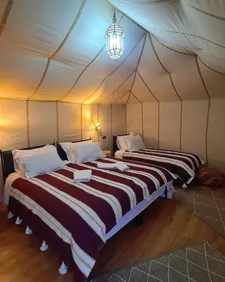 two beds in a room with a tent at Luxury Desert Camp Merzouga in Merzouga