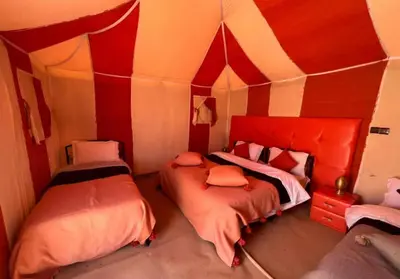 two beds in a room with red and white walls at Glamping luxury camp in Merzouga