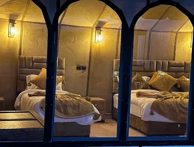 a bedroom with two beds and a large window at Glamping luxury camp in Merzouga