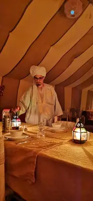 a chef standing behind a table in a room at Chez Sadoq Luxury Camp in Merzouga