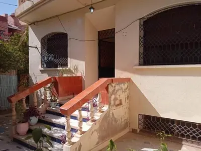 a house with a wooden staircase in front of a building at Rez-de-chaussée villa touta in Beni Mellal