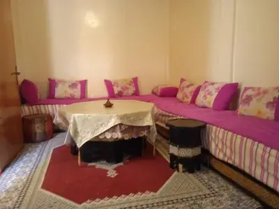 a room with two beds and a table and a couch at Rez-de-chaussée villa touta in Beni Mellal