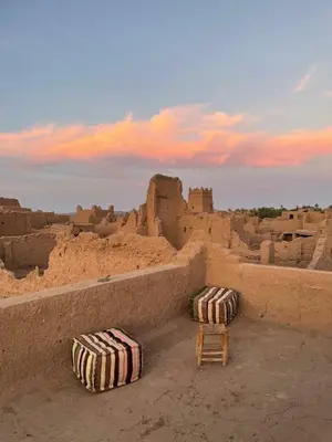 two beach umbrellas and two chairs in front of a castle at Dar Nuyum in Bou Nou