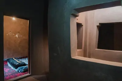 a bathroom with a mirror and a room with a bed at Dar Nuyum in Bou Nou