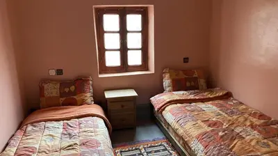 two twin beds in a room with a window at Riad Bouchahoud Hotel in Telouet in Telouet