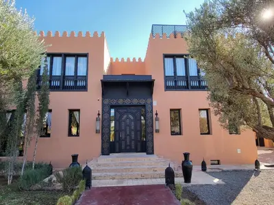 a large orange building with a black door at Villa Chems - Al Ouidane in Marrakech
