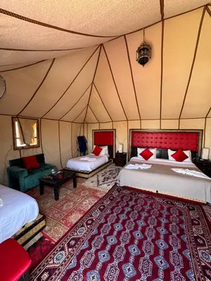 a bedroom with two beds and a rug in a tent at Super Luxury camp in Merzouga