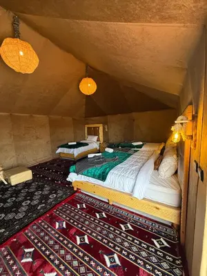 an attic room with two beds and a rug at Super Luxury camp in Merzouga