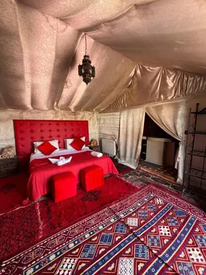 a bedroom with a red bed in a tent at Super Luxury camp in Merzouga
