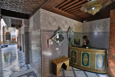 a woman sitting at a desk with a laptop in a room at Riad Semlalia in Fès