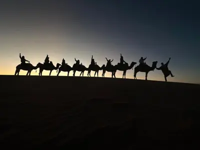 a group of people riding horses in the desert at Sahara Dunes Camp in Merzouga