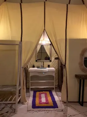 a bathroom with a tent with a sink and a mirror at Sahara Dunes Camp in Merzouga