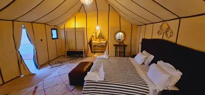 a bedroom with a large bed in a tent at Sahara Dunes Camp in Merzouga