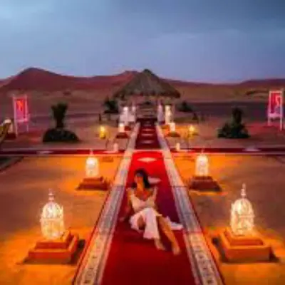 a woman sitting on a red bus in the desert at Merzouga Top Luxury Camp in Merzouga