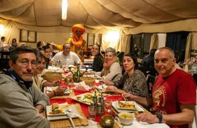 a group of people sitting at a table eating food at Merzouga Top Luxury Camp in Merzouga