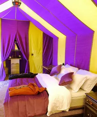 a bedroom with a purple and yellow tent at Luxury Camp Rachid in Merzouga