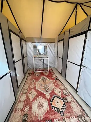 an inside view of a tent with a rug on the floor at Luxury Camp Rachid in Merzouga