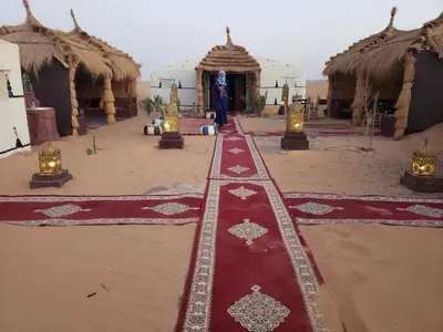 a room with a red carpet and some huts at Luxury Camp Rachid in Merzouga