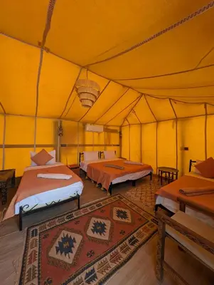 a large yellow tent with two beds in it at Luxury Desert Camp Merzouga with Air Conditioning and Heating in Merdani