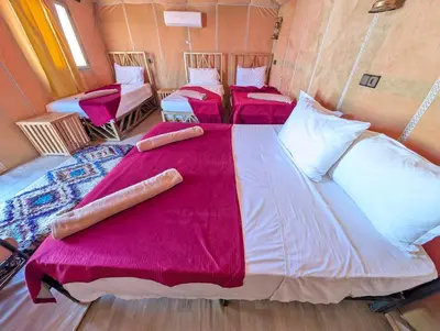 two beds in a room with red sheets at Luxury Desert Camp Merzouga with Air Conditioning and Heating in Merdani