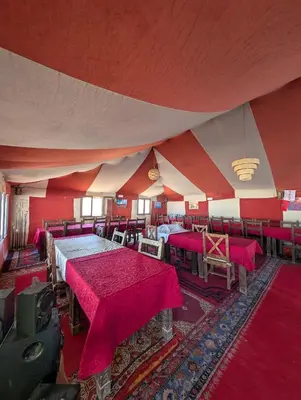 a room with tables and chairs in a tent at Luxury Desert Camp Merzouga with Air Conditioning and Heating in Merdani