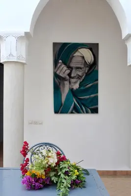 a table with flowers and a painting on the wall at Villa Agora, Villa à la campagne proche Marrakech in Marrakech
