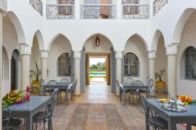 a hallway with tables and chairs in a building at Villa Agora, Villa à la campagne proche Marrakech in Marrakech