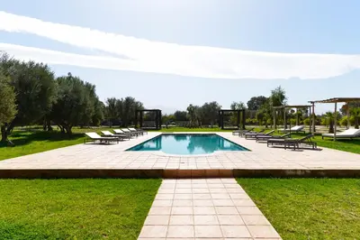 a swimming pool in a park with chairs around it at Villa Agora, Villa à la campagne proche Marrakech in Marrakech