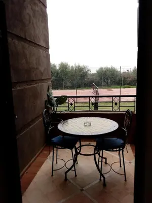 a table and chairs on a balcony with a view of a field at Villa Malaa'ika in Marrakech
