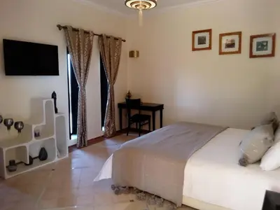 a bedroom with a bed and a desk and a television at Villa Malaa'ika in Marrakech