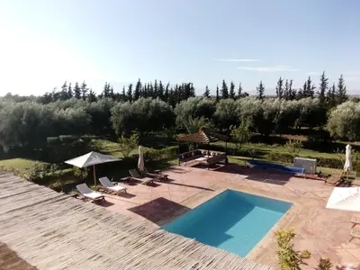 a swimming pool with lounge chairs and an umbrella at Villa Malaa'ika in Marrakech