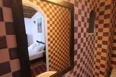 a mirror in a bathroom with a bed in a room at Bejaad in Boujad