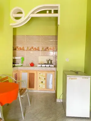 a small kitchen with green walls and a refrigerator at Boka Dunes Houses Merzouga in Merzouga