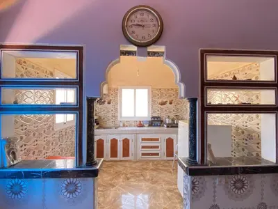 a kitchen with a clock on the wall and two windows at Boka Dunes Houses Merzouga in Merzouga