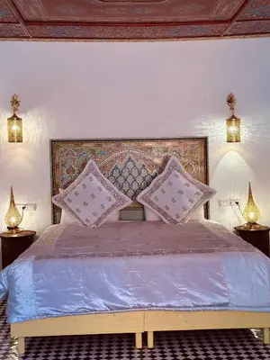 a bedroom with a large bed with pillows on it at Riad Damia Suite & Spa in Fès