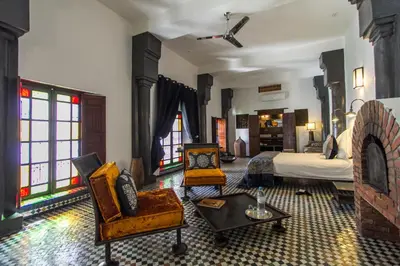 a bedroom with a bed and chairs and a fireplace at Riad Laaroussa in Fès