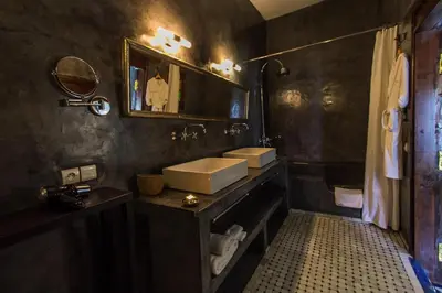 a black bathroom with a sink and a mirror at Riad Laaroussa in Fès