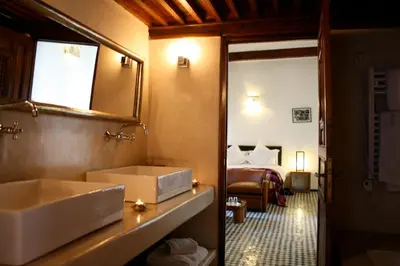 a bathroom with a sink and a mirror and a bed at Riad Laaroussa in Fès