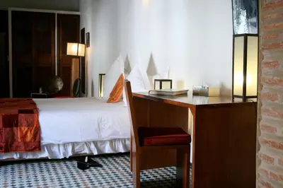 a bedroom with a white bed and a desk at Riad Laaroussa in Fès